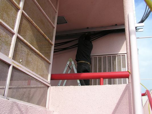 10. Securing the Coaxial Cables in the Tray
A tech secures the cables to the tray.  Notice that the cable tray extends out a bit from the edge of the wall.  This will connect with the vertical portion of the tray heading to the roof.
Keywords: verizon armacost
