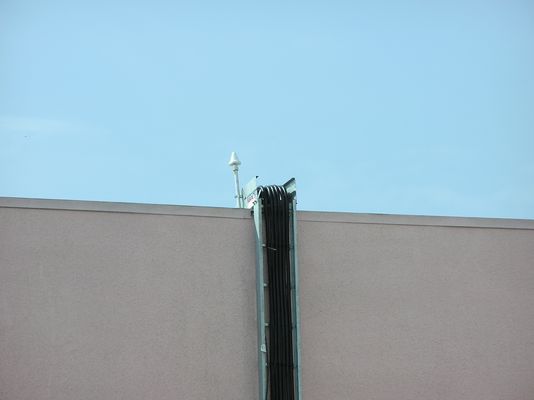 12. Close-up of GPS antenna and top of Cable Tray
As noted before, the cables are carefully pulled on to the roof so as to prevent kinks.  The GPS antenna provides system synchronization time signals.  This location is inferior as it can been seen from the ground.  A better location would have been on the roof away from the edge so as to hide this element.  
Keywords: verizon armacost