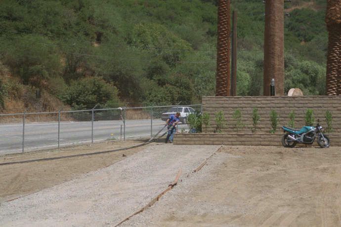 Getting ready for pulling the coax cables up the tree
The worker prepares the coax cables for insertion into the trunk of the monopalm by laying them out flat on the ground.  From here, a pull rope will be used to raise the cables into the trunk, and up to the level of the antennas.
Keywords: build monopalm coax cable pull rope