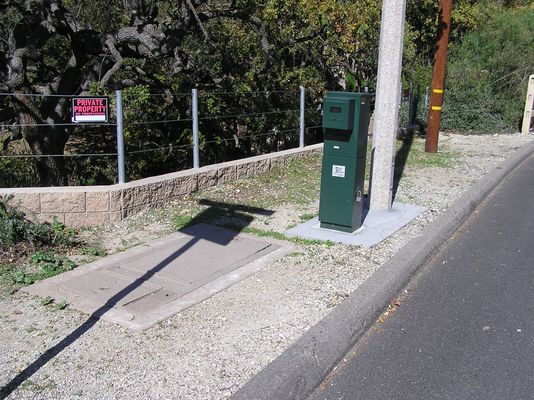 Cingular underground cell site equipment
The BTS equipment vault, in the foreground, serves a  Cingular's light standard microcell.  The green pedestal houses the power company meter, and is subject to removal if the power company allows unmetered or remotely metered service sometime in the future.
Keywords: cingular microcell light standard base station vault