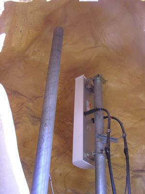 Peeking Inside a Wireless Rock
This is what an antenna looks like mounted inside a cellular rock.  The two coaxial cables indicate that the antenna is actually two antennas inside one radome: one for transmit, and one for receive.  Another panel antenna can easily be added on the mounting pole in the foreground.
