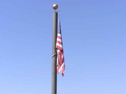 Cingular Flag Pole (Close-up)
This photograph highlights the reason for conditioning wireless flag pole sites flying the American Flag to routinely inspect the condition of flag, and to follow the requirements of the United States Code, Title 36, Chapter 10.  As seen in this photo, the US Flag on the Cingular camo flag pole is tattered.
Keywords: Cingular tattered US flag flagpole pole