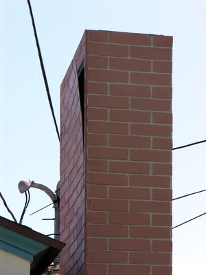 Close Up of Top of Poorly Maintained Faux Chimney
This Cingular-built site in El Segundo, California, now owned by T-Mobile, overlooks LAX.  The building houses a mortuary.  In this picture you see a very poorly maintained faux chimney.  A brick facade panel is coming off.  The cable, telephone, and power drops should be relocated to achive the required NEC clearances.
Keywords: cingular t-mobile lax el segundo faux chimney steeple