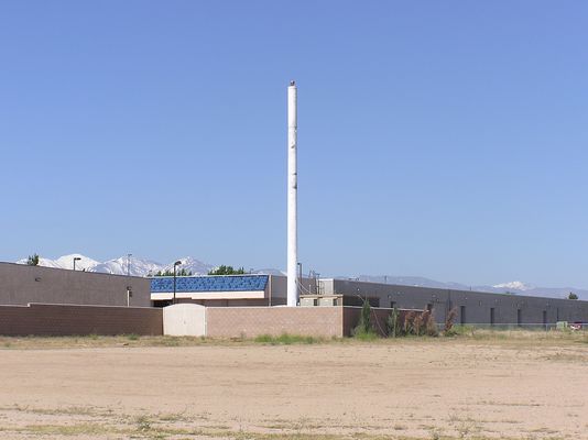 It's a Grand Old Flagpole?
Verizon's flagpole site in Hesperia, California lacks, well, a flag.  Note the wind/sand damage to the pole finish.  If you look carefully, you'll see the rope used to hoist the flag has come down and is resting on top of the the equipment building, then falling to the ground to the right of the building.  Nice job in site maintenance.
Keywords: verizon flagpole hesperia california flag pole