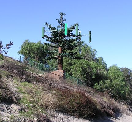 18 - Our little friend has changed and grown!
This photo, taken in November, 2004 shows (1) that the second-to-the-right antenna has been changed out without much regard to color matching, (2) that a new dual-band antenna has been added on trunk below the prior-existing antennas, and (3) that the faux branches have been extended down the trunk to provide partial cover for the new antenna.  

Note that the replacement dual-band antenna has its four cable ports visible on the bottom of the antenna, unlike the existing with hidden rear connectors.  Most unsightly!

Sad, sad little tree.
Keywords: i405 tree