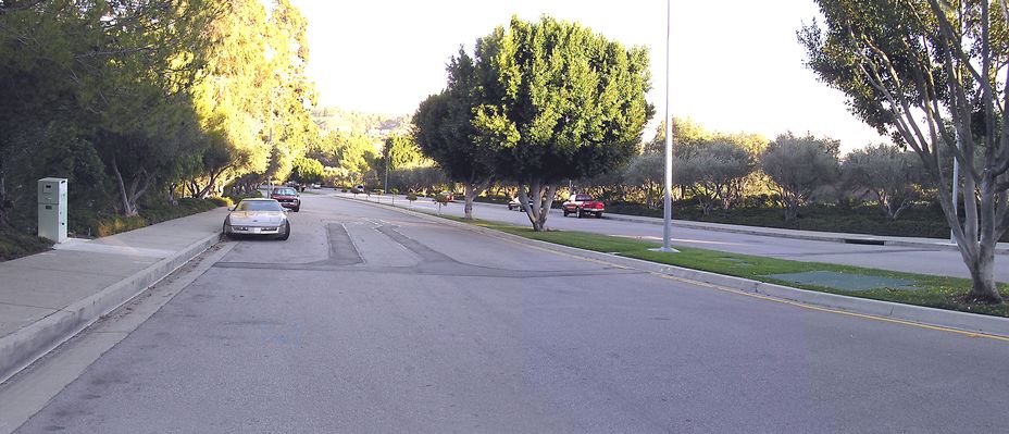 Panoramic view of Sprint Mountaingate Monopole
This panoramic photo show the street cuts from power (left), telephone (right), the power meter (far left), the BTS equipment vault and vents in the traffic median, the street cut from the median to the antenna pole (far side of median), and the base of the antenna pole (far right, behind tree).  The pole in the middle of the traffic median is a two-arm street light.  Too bad it (or a replacement) wasn't used to support the antenna.  That would have eliminated the need for the standalone pole just to support the single panel antenna.
Keywords: Sprint Mountaingate