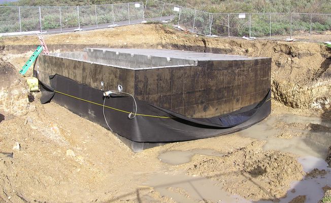 Hey, it's a good thing they got the weatherproofing on the building!
It's been raining 'round our soon-to-be underground friend.  Notice that the conduits are extended through the precast holes.
Keywords: KMLT